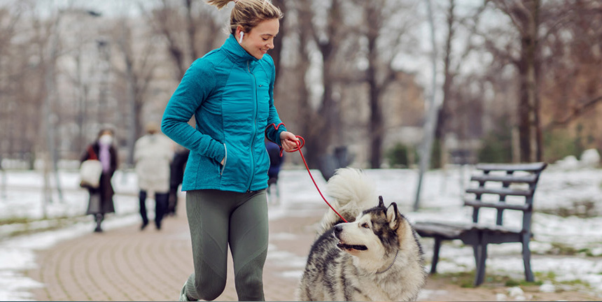 A woman in a black winter jacket with comfortemp® insulation talking on the phone and walking her bicycle.