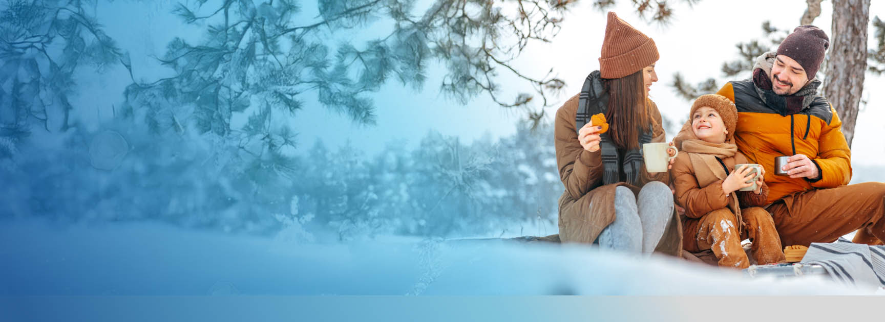 Family enjoying a winter picnic in insulated outerwear, comfortemp® insulation providing warmth in snowy conditions.